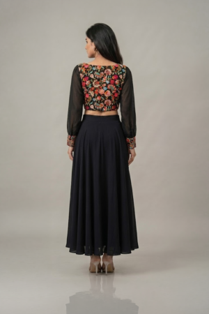 Woman wearing a black floral embroidered dress with sheer sleeves and a flowing flared skirt