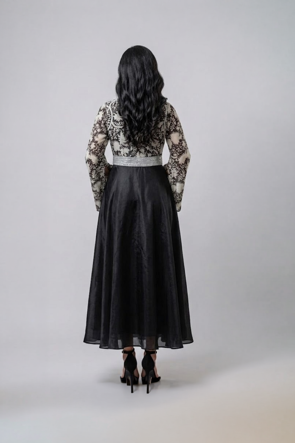 Woman wearing a black gown with a monochrome printed wrap bodice, flared kimono sleeves and a flowing maxi skirt