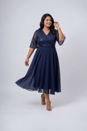 Woman wearing a midnight navy sequin gown with a wrap V-neckline, elbow-length sleeves and a flowing A-line skirt