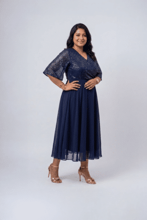 Woman wearing a midnight navy sequin gown with a wrap V-neckline, elbow-length sleeves and a flowing A-line skirt