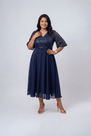 Woman wearing a midnight navy sequin gown with a wrap V-neckline, elbow-length sleeves and a flowing A-line skirt