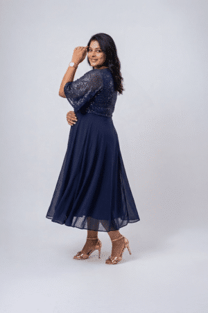 Woman wearing a midnight navy sequin gown with a wrap V-neckline, elbow-length sleeves and a flowing A-line skirt