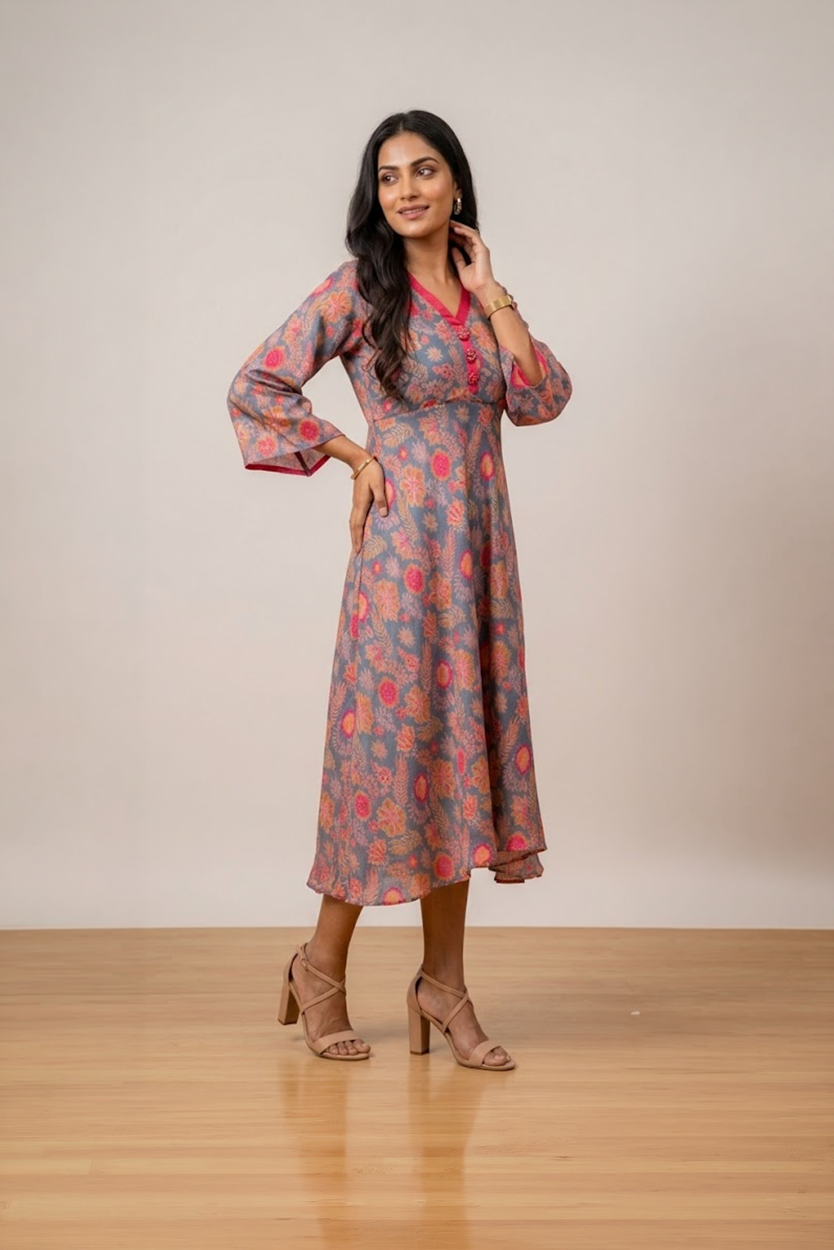 Woman wearing a grey floral print midi dress with a V-neckline, three-quarter bell sleeves and a flared silhouette