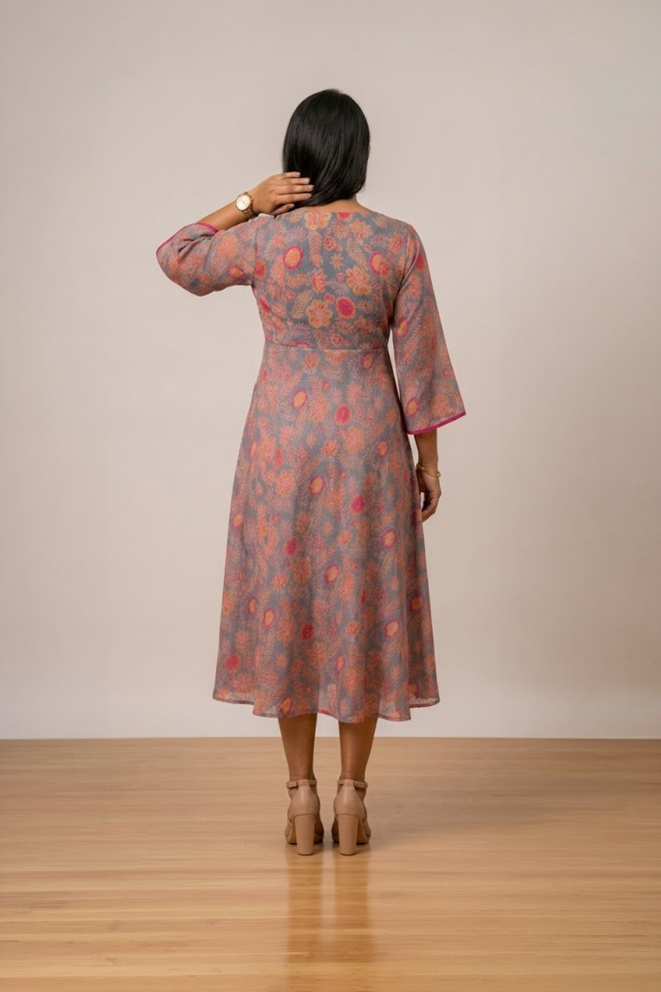 Woman wearing a grey floral print midi dress with a V-neckline, three-quarter bell sleeves and a flared silhouette