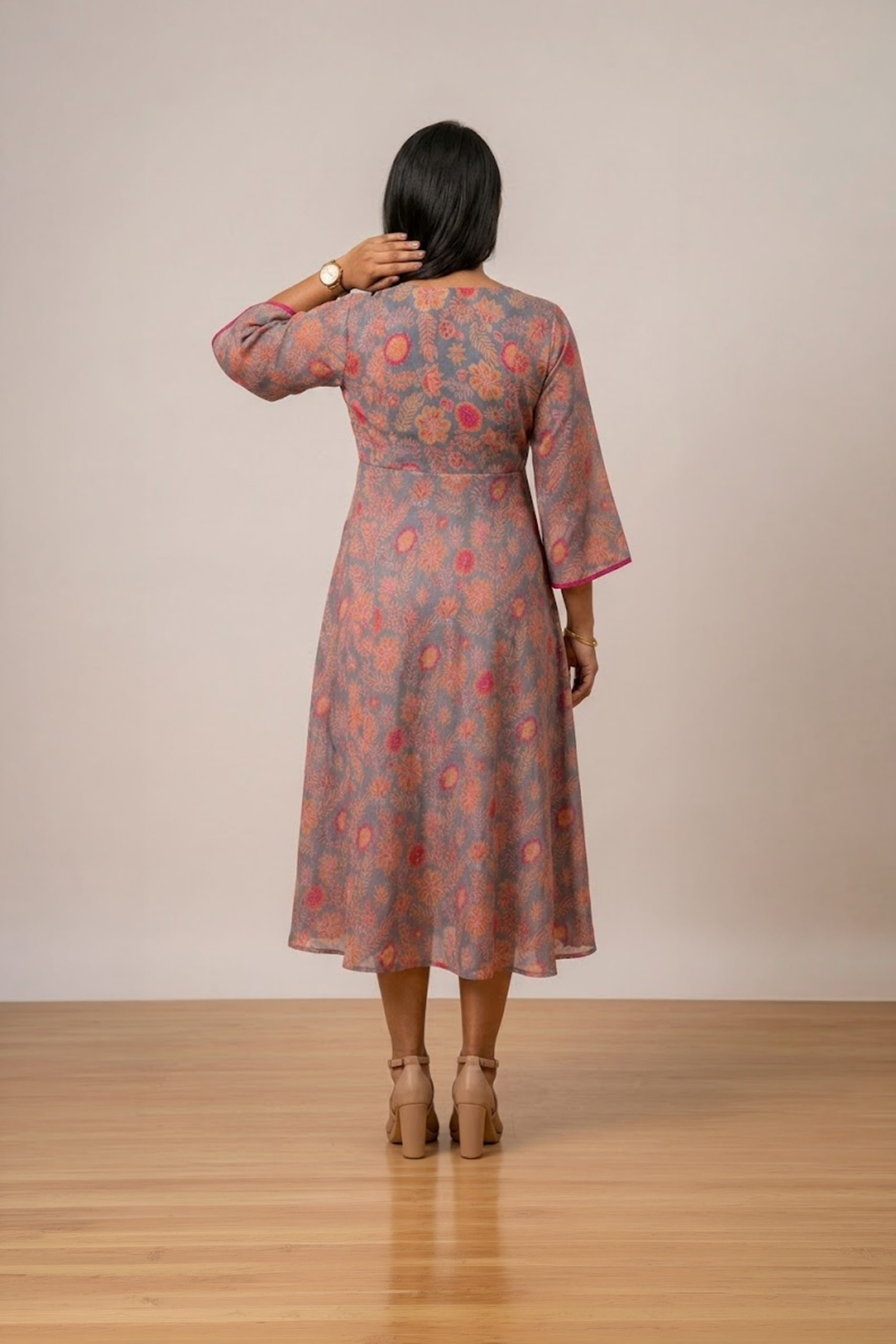 Woman wearing a grey floral print midi dress with a V-neckline, three-quarter bell sleeves and a flared silhouette