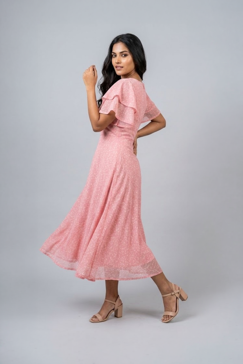 Woman wearing a soft pink midi dress with layered flutter sleeves and a flowing A-line silhouette