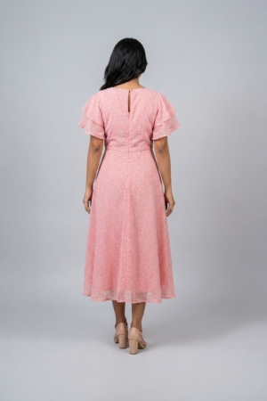 Woman wearing a soft pink midi dress with layered flutter sleeves and a flowing A-line silhouette