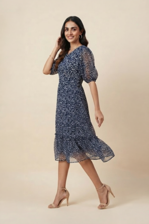Woman wearing a navy blue floral ruffle midi dress with a V-neckline and sheer puff sleeves