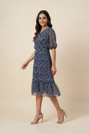 Woman wearing a navy blue floral ruffle midi dress with a V-neckline and sheer puff sleeves