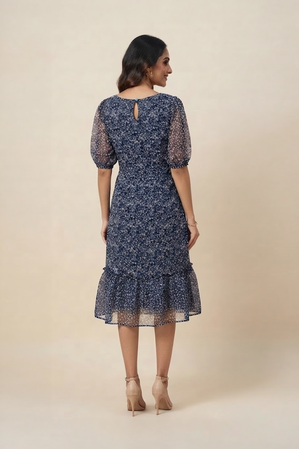 Woman wearing a navy blue floral ruffle midi dress with a V-neckline and sheer puff sleeves