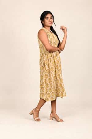 Yellow and beige Ajrakh cotton sleeveless dress, three-quarter side pose with nude ankle-strap sandals