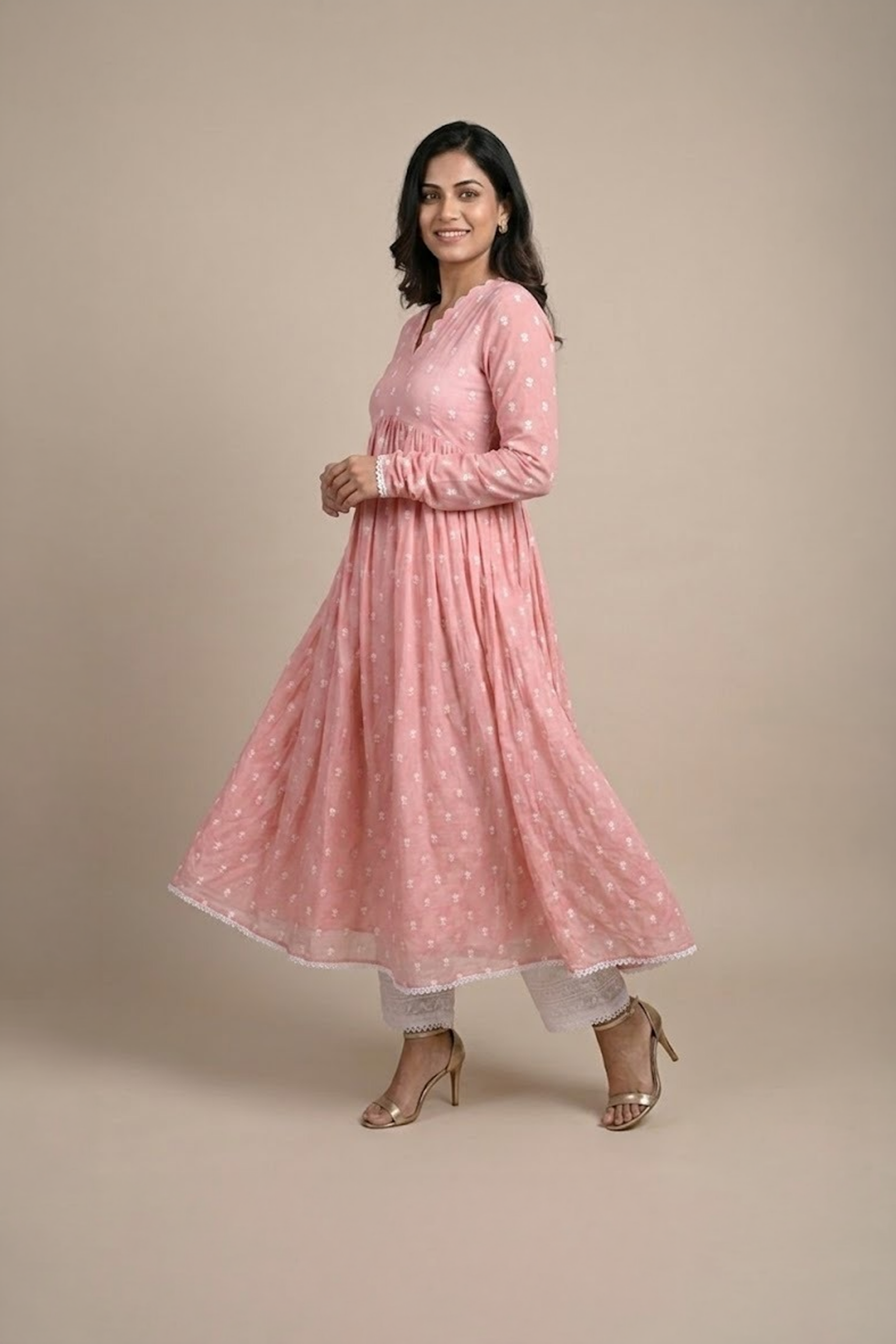 Woman wearing a dusty pink embroidered Anarkali with a scalloped V-neckline, long sleeves and white pants