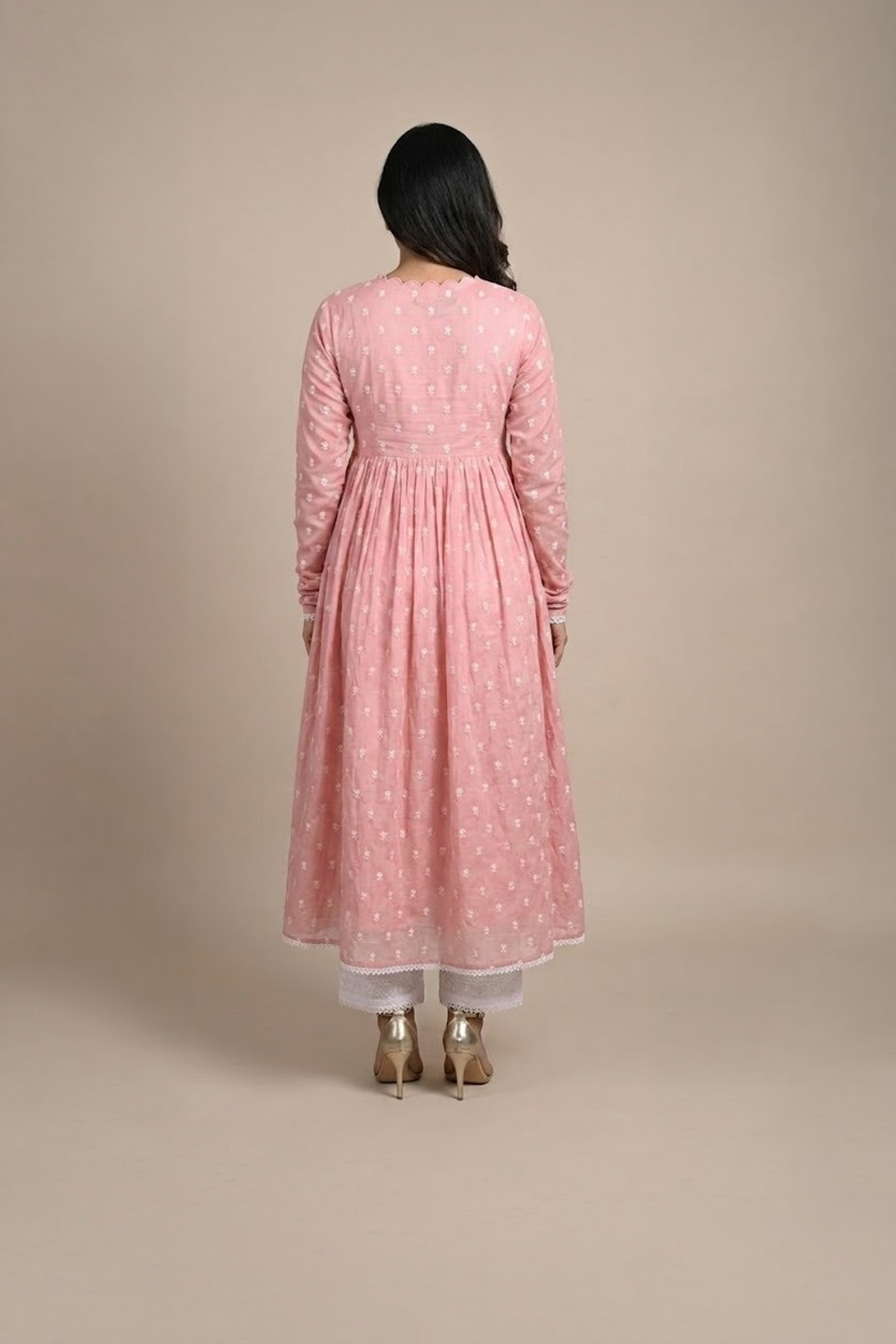 Woman wearing a dusty pink embroidered Anarkali with a scalloped V-neckline, long sleeves and white pants