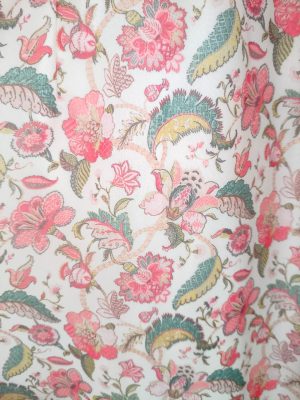 Woman standing and posing in a long floral dress with full sleeves and a V-neckline.