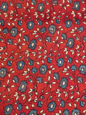 "Woman wearing a red floral printed long A-line dress with full sleeves, posing against a beige background"