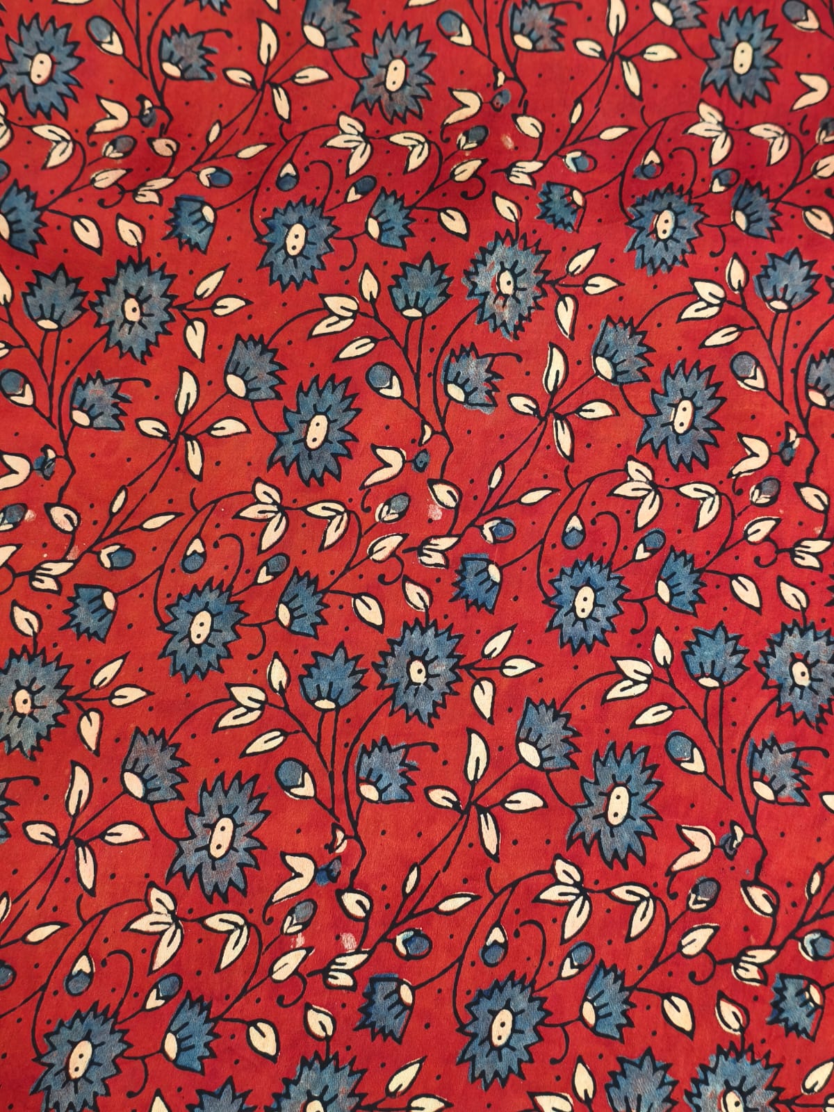 "Woman wearing a red floral printed long A-line dress with full sleeves, posing against a beige background"