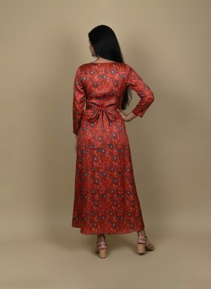 "Woman wearing a red floral printed long A-line dress with full sleeves, posing against a beige background"