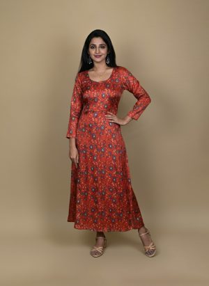 "Woman wearing a red floral printed long A-line dress with full sleeves, posing against a beige background"