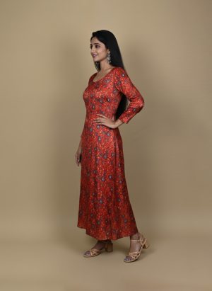 "Woman wearing a red floral printed long A-line dress with full sleeves, posing against a beige background"