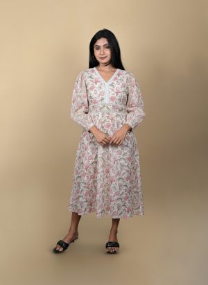 "Full view of a woman wearing a white and pink floral midi dress with long sleeves and lace detailing, posing against a beige background"
