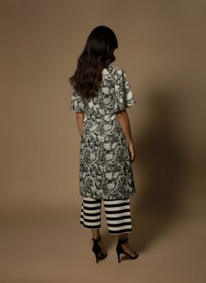 Model wearing a black and white printed cotton kurta set with sleeveless V-neck kurta and striped palazzo pants from Ivory by Radhika.
