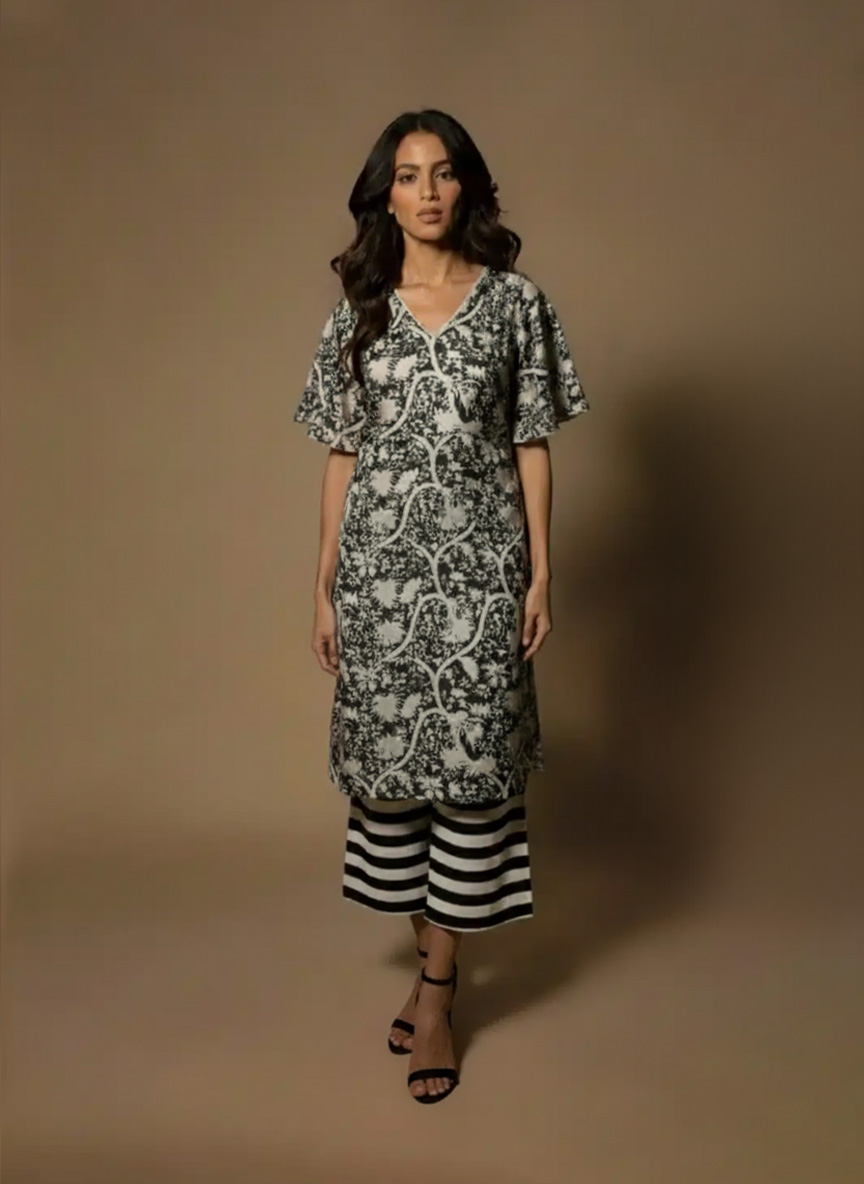 Model wearing a black and white printed cotton kurta set with sleeveless V-neck kurta and striped palazzo pants from Ivory by Radhika.