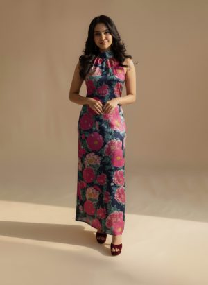 Model wearing a navy blue floral maxi dress with a halter neckline and bold pink floral prints from Ivory by Radhika.
