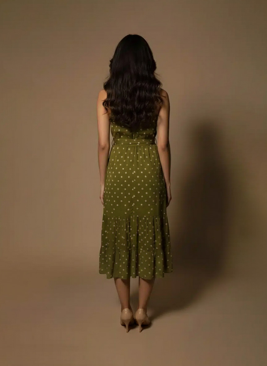 Model wearing an olive green halter neck midi dress with polka dots and a satin waist tie from Ivory by Radhika.