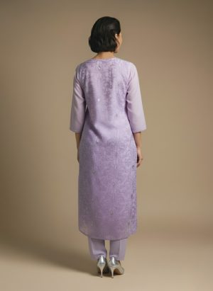Woman standing and smiling, wearing a light lavender kurta with subtle patterns and matching pants.