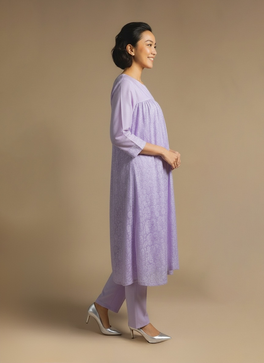 Woman standing and smiling, wearing a light lavender kurta with subtle patterns and matching pants.