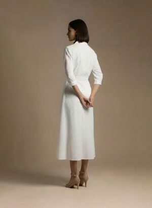 woman wearing a white cotton eyelet shirt dress with three quarter sleeves and waist tie