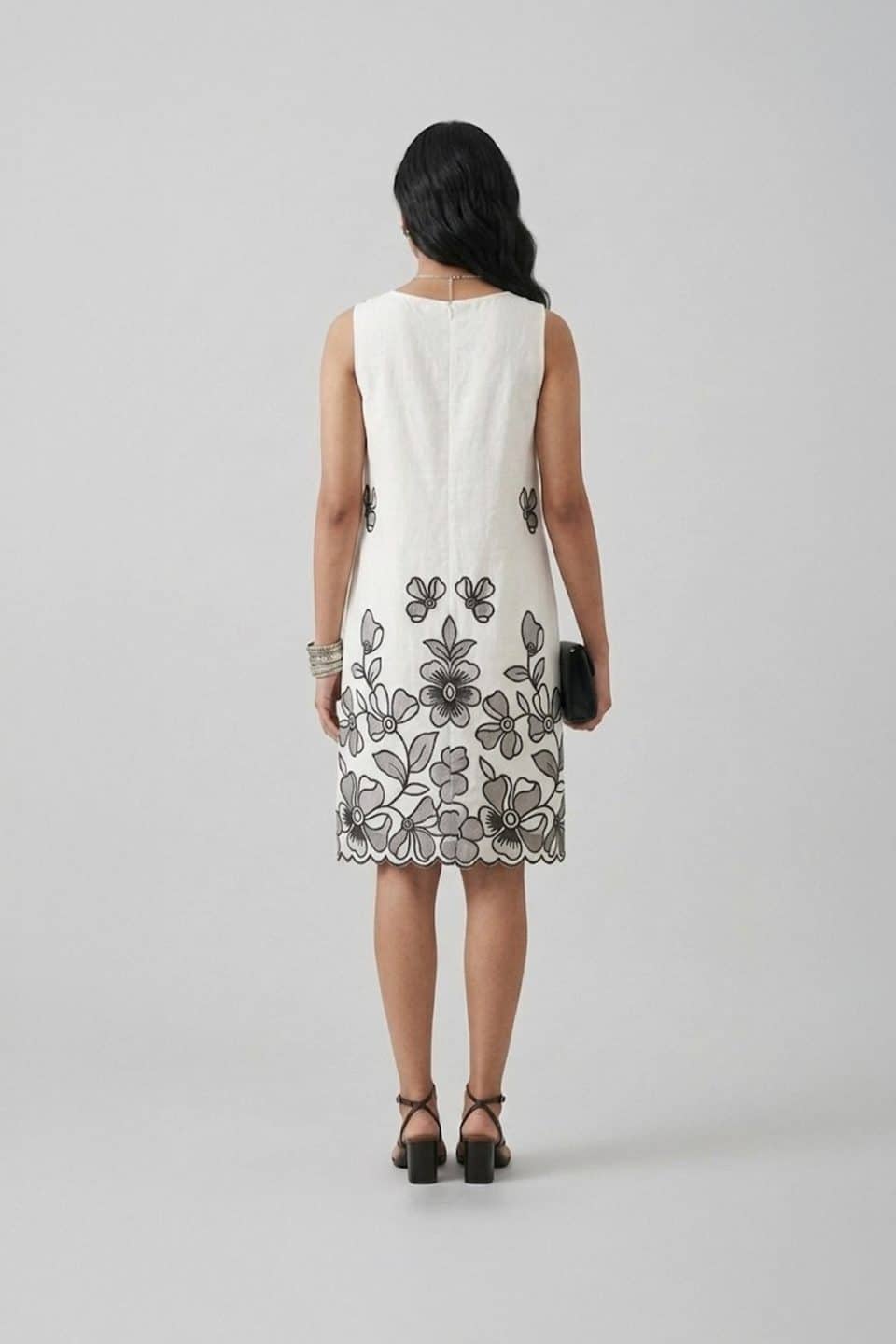 Elegant white sleeveless A-line dress with black floral embroidery and scalloped hem, perfect for summer brunch and resort wear.