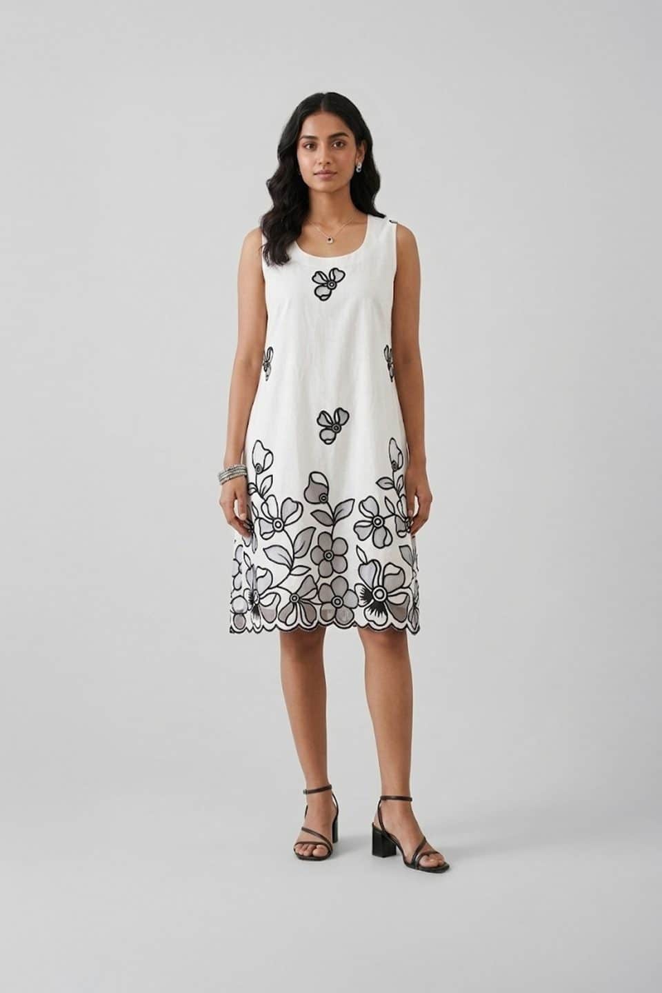 Elegant white sleeveless A-line dress with black floral embroidery and scalloped hem, perfect for summer brunch and resort wear.