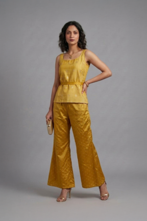 Woman wearing mustard silk co-ord set with sleeveless top and flared pants