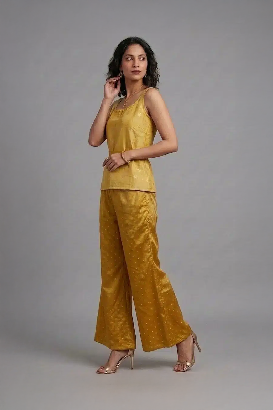 Woman wearing mustard silk co-ord set with sleeveless top and flared pants