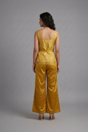 Woman wearing mustard silk co-ord set with sleeveless top and flared pants