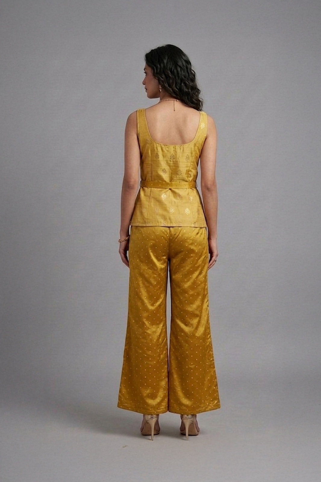 Woman wearing mustard silk co-ord set with sleeveless top and flared pants