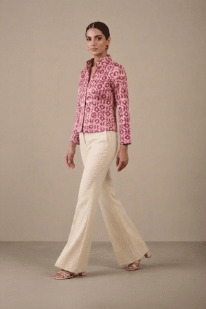 Side view of pink geometric-print short jacket on model walking in ivory trousers