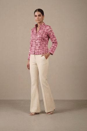 Three-quarter front view of pink geometric-print short jacket styled with ivory trousers