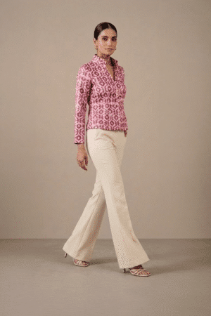 Three-quarter walking view of pink and ivory geometric-print short jacket on model