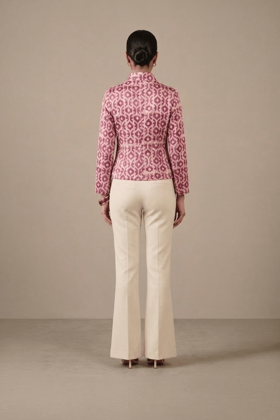 Back view of pink and ivory geometric-print short jacket showing full sleeves and hip-length hem