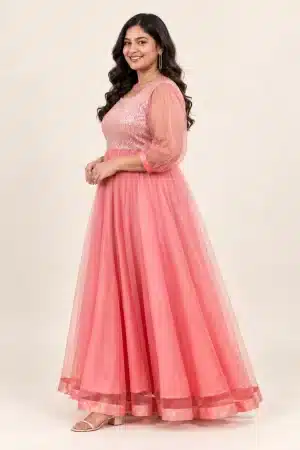Side view of coral pink shimmering tulle gown on a plus-size model