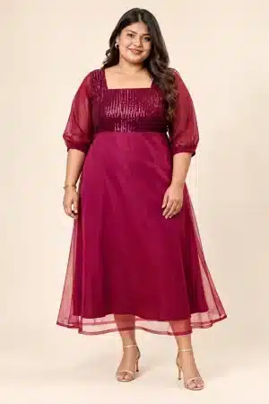 Front view of a plus-size model wearing the Maroon Sequin Elegance Gown with sheer puff sleeves and champagne-gold sandals
