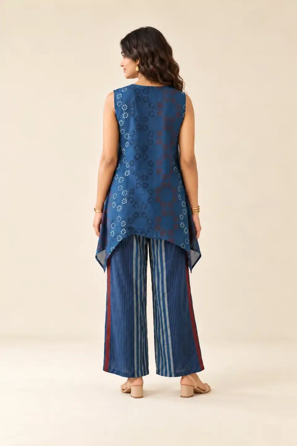Back view of blue sleeveless Modal Ajrakh tunic and striped wide-leg trousers, styled with gold jewellery.