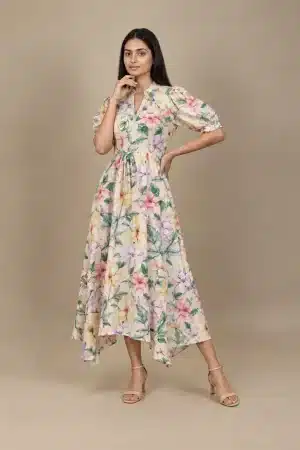 Pastel Floral High Low Dress in beige with multicolour flowers, front angled view with hand near chin.